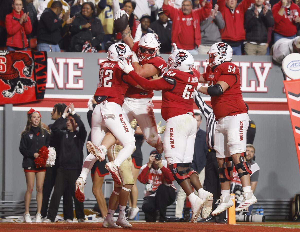 N.C. State’s Preston Douglas (82), Rico Jackson (64), Teague Andersen (54) celebrate with Cody Hardy (44) after Hardy pulled in a five-yard touchdown reception in the first half of N.C. State’s game against Georgia Tech at Carter-Finley Stadium in Raleigh, N.C., Saturday, Nov. 1, 2025.