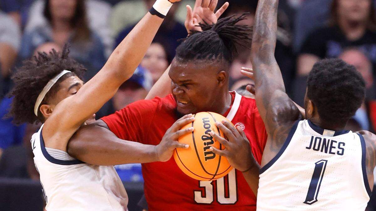 On review, Marquette’s Stevie Mitchell (4) is called for a foul on N.C. State’s DJ Burns Jr. (30) as Marquette’s Kam Jones (1) also defends during the first half of N.C. State’s game against Marquette in their NCAA Tournament Sweet 16 game at the American Airlines Center in Dallas, Texas, Friday, March 29, 2024.