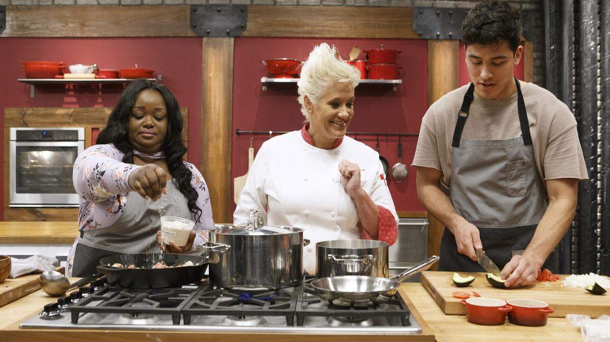 Mentor Anne Burrell, center, checks in on recruits Janese Henry and Bradley Garcia as they cook during the baseline challenge on Food Network’s “Worst Cooks in America,” Season 14.