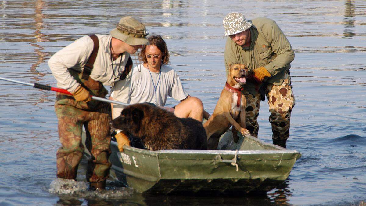 This Sept. 9, 2005 photo provided by Best Friends Animal Society shows a volunteer, center with Best Friends Animal Society rescue team members Ethan Gurney, left, and Jeff Popowich, right, retrieving dogs from the floods of Hurricane Katrina in New Orleans.