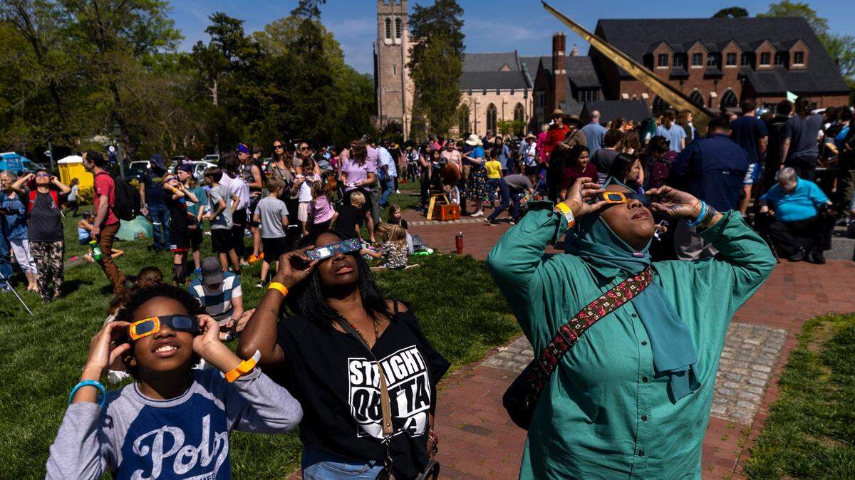 From left, Amir Foushee, 12, Chandra Dunston and Paris Miller-Foushee wear protective glasses while viewing the solar eclipse during a watch party at the Morehead Planetarium and Science Center at UNC-Chapel Hill on Monday, April 8, 2024.