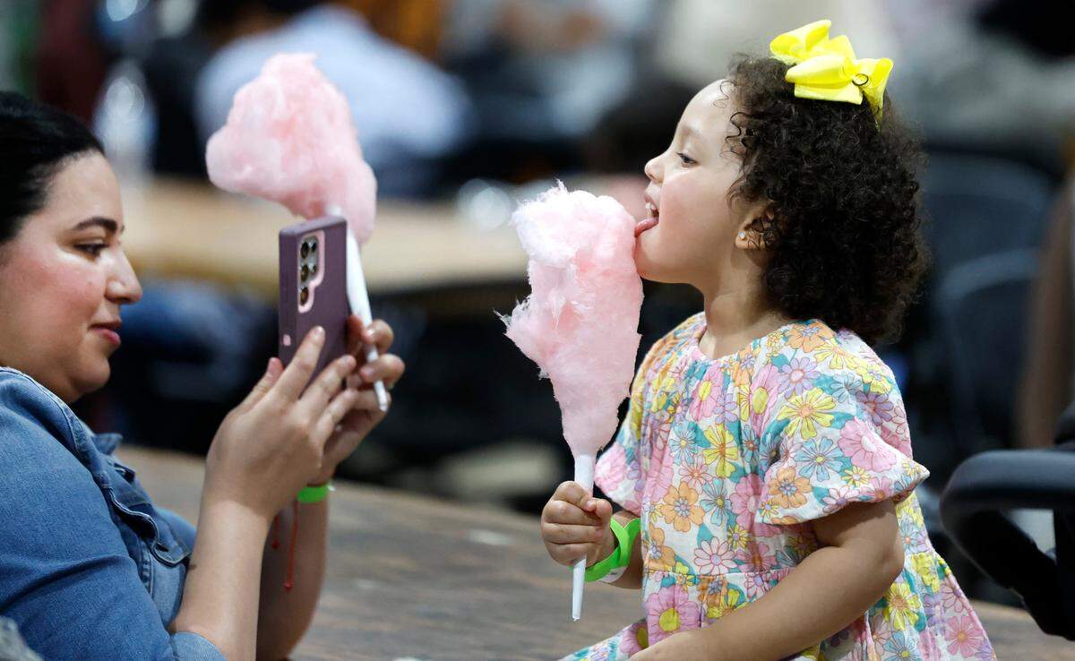 Sanaa Achik takes a photo of her daughter Jana Bendhiba, 2, as she enjoys cotton candy during the Eid Festival at the Jim Graham Building in Raleigh, N.C. Saturday, June 22, 2024. Eleven Triangle mosques and Islamic organizations joined forces to hold what was billed as North Carolina’s largest Eid festival.