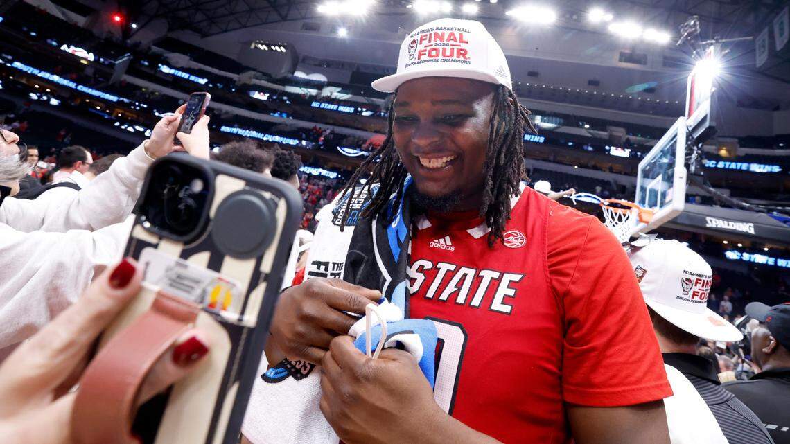 N.C. State’s DJ Burns Jr. (30) FaceTimes with the Wolfpack women’s basketball team after their 76-64 victory over Duke in their NCAA Tournament Elite Eight matchup at the American Airlines Center in Dallas, Texas, Sunday, March 31, 2024.