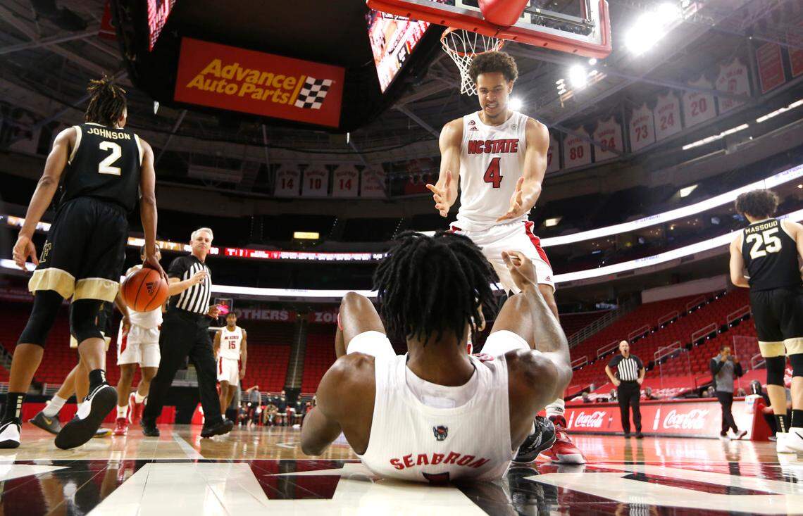 N.C. State’s Jericole Hellems (4) comes over to help Dereon Seabron (1) up after he was fouled while driving to the basket during N.C. State’s 72-67 victory over Wake Forest at PNC Arena in Raleigh, N.C., Wednesday, January 27, 2021.