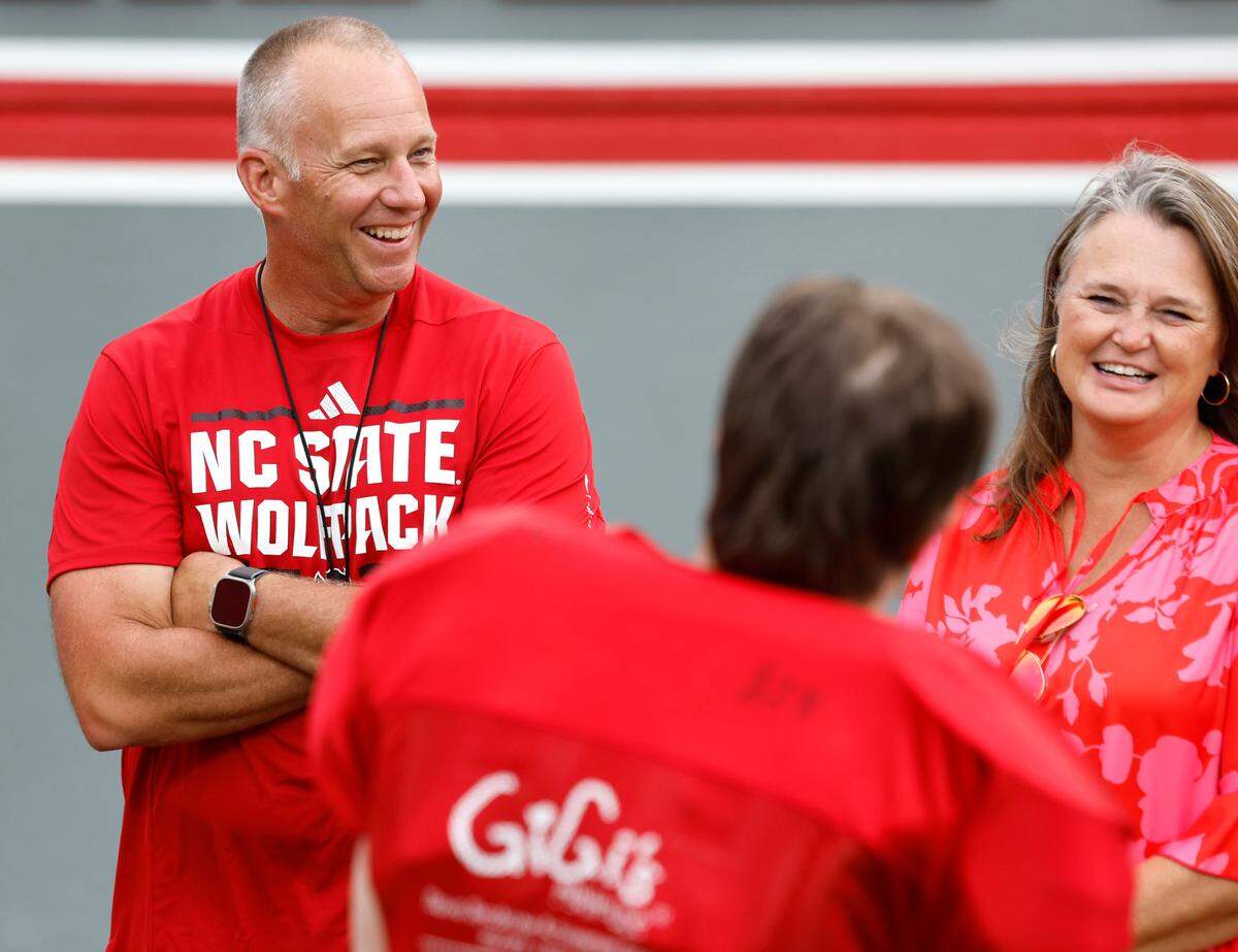 N.C. State head football coach Dave Doeren and his wife Sara talk with Sam Hening during Victory Day at Carter-Finley Stadium in Raleigh, N.C., Friday, August 2, 2024.