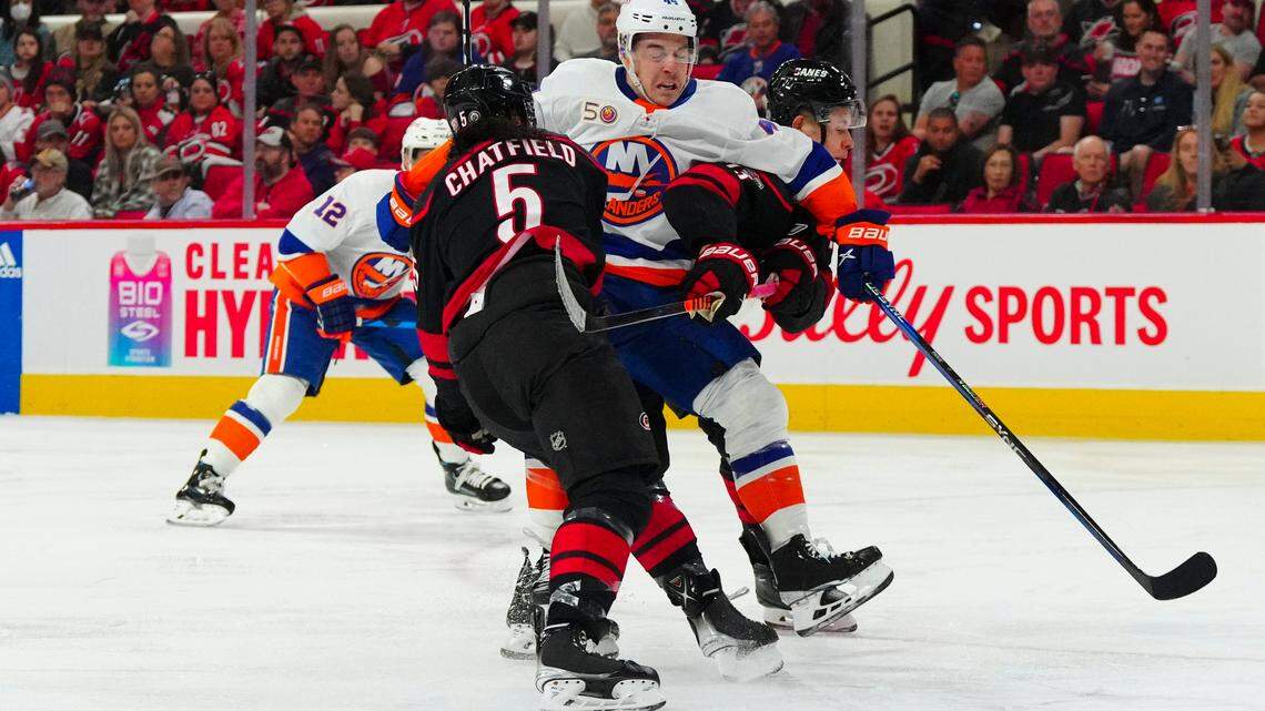 New York Islanders center Jean-Gabriel Pageau (44) is checked by Carolina Hurricanes defenseman Jalen Chatfield (5) and right wing Jesse Puljujarvi (13) during the second period at PNC Arena.