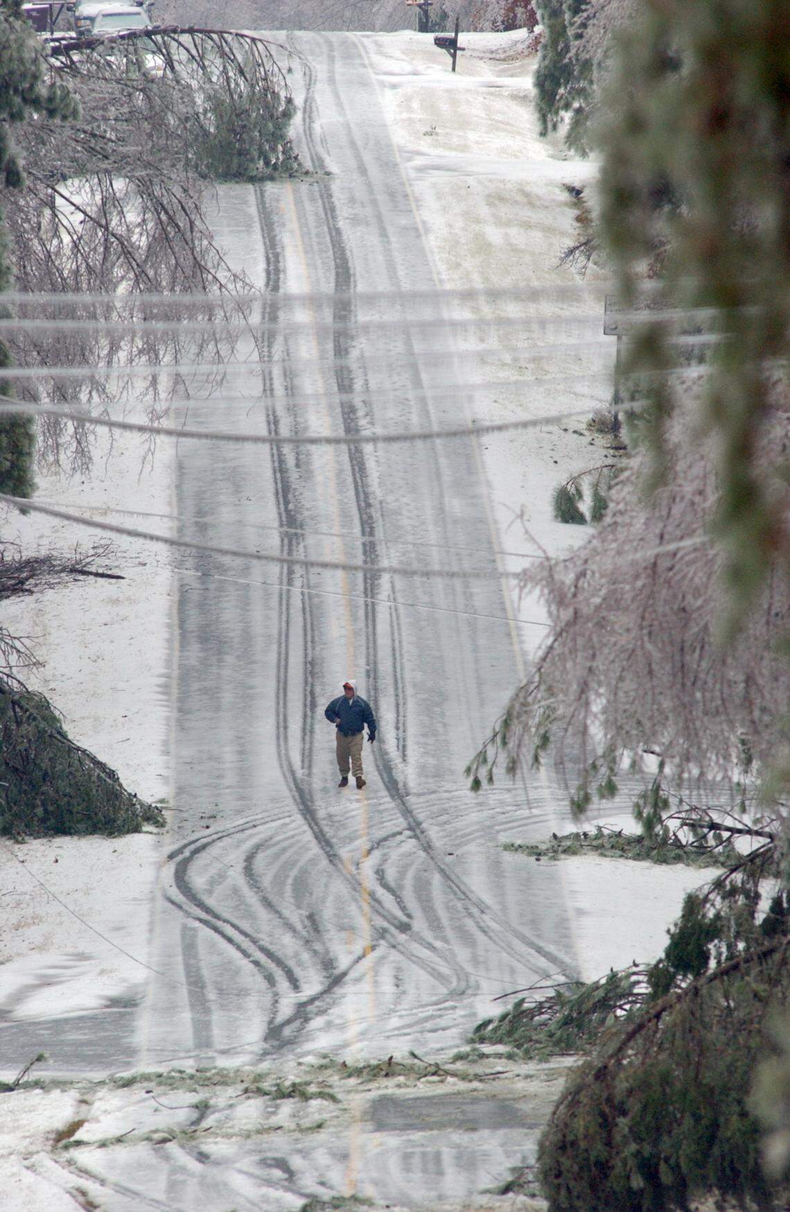 Bill Harvey walks down Matthews Road in north Durham County among downed trees  as he checks his neighborhood, which is off Mason Road.  The ice buildup caused power lines to break as well as tree limbs and whole trees to fall on the lines, causing widespread power outages in the Triangle area.