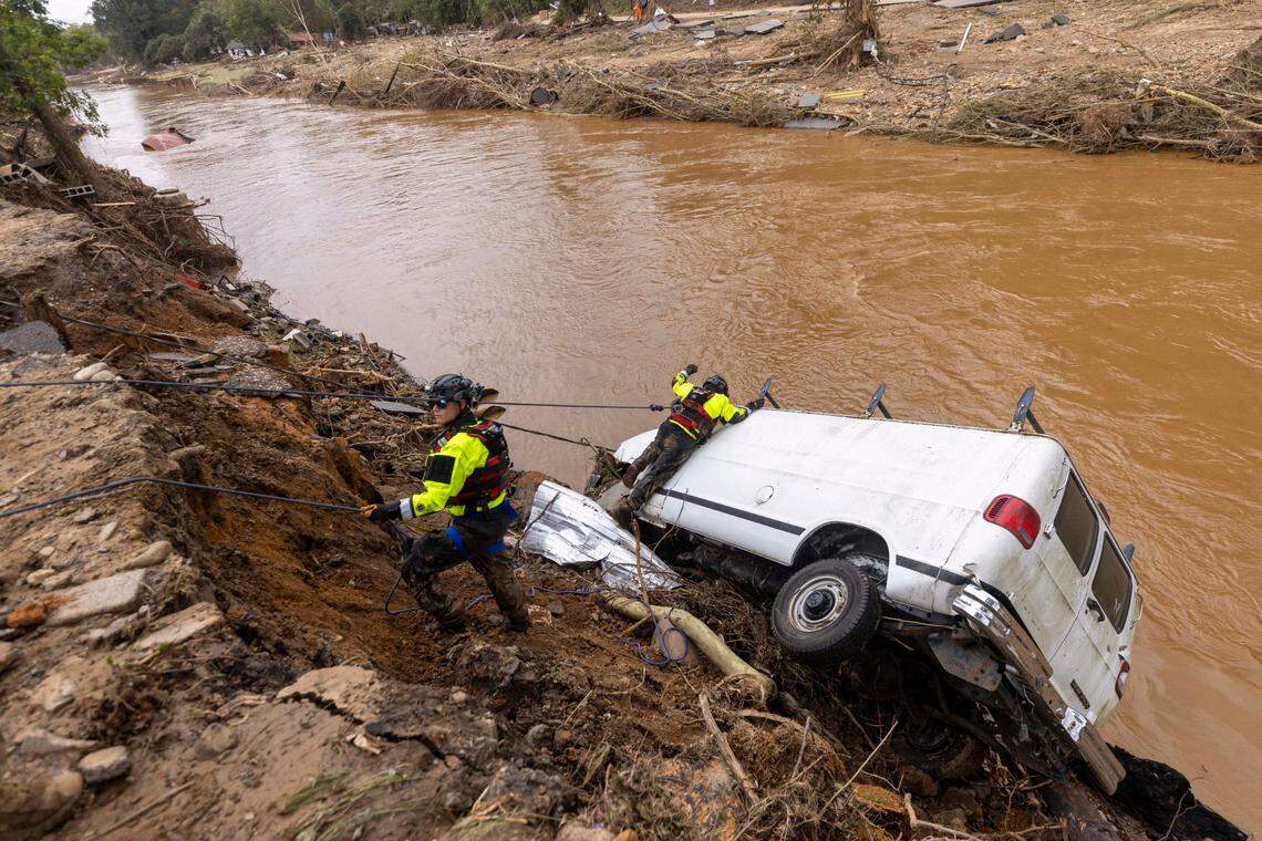A search and rescue team out of Atlantic Beach, N.C. examines a van swept into the river in Swannanoa, N.C. by flooding from Helene. They were assisting in the community, Sunday, Sept. 29, 2024.