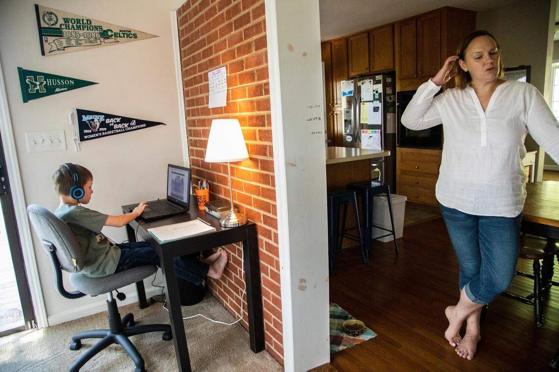 Eli Spencer, a second-grader at Powell Center for Play and Ingenuity Magnet Elementary uses a laptop to participate in a remote learning assignment as his mother Jenny Spencer looks on at their home in Raleigh in this file photo from 2020. 