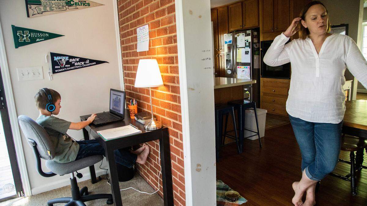 Eli Spencer, a second-grader at Powell Center for Play and Ingenuity Magnet Elementary uses a laptop to participate in a remote learning assignment as his mother Jenny Spencer looks on at their home in Raleigh in 2020. File photo.