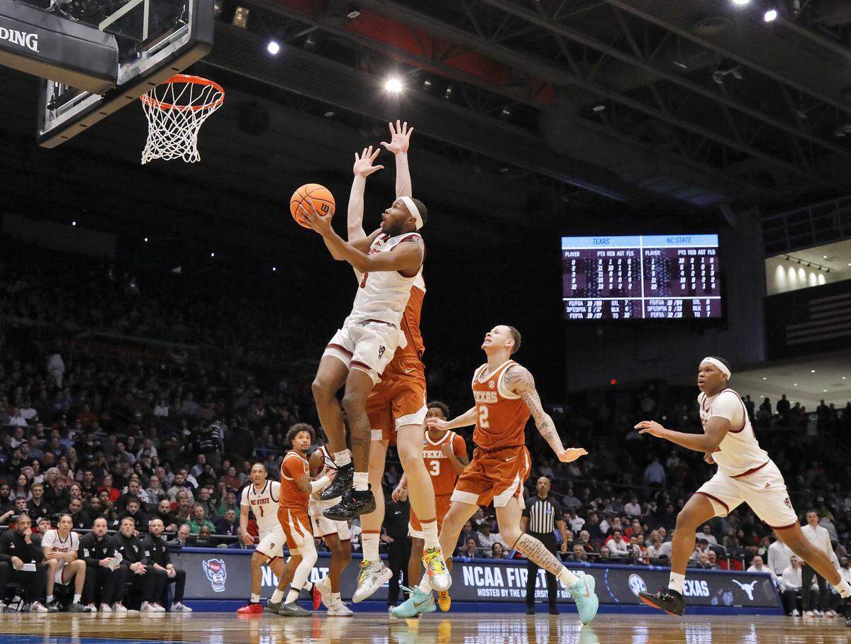 N.C. State’s Tre Holloman drives to the basket past Texas’ Matas Vokietaitis and Chendall Weaver during the second half of the Wolfpack’s 68-66 loss in the NCAA First Four on Tuesday, March 17, 2026, at the University of Dayton Arena in Dayton, Ohio. 