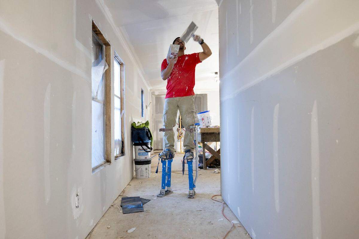 Jose Hernandez installs dry wall in a home that was damaged by flood waters from Hurricane Helene in the Bradford Park mobile home park on Tuesday, November 26, 2024 in Boone, N.C.