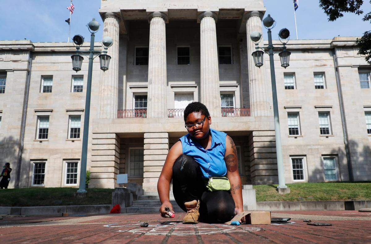Kiara Sanders works on a chalk portrait of Abraham Galloway outside the State Capitol in Raleigh, N.C., Saturday, June 19, 2021. As part of Juneteenth commemorations, Sanders drew the portrait of Galloway, a former slave, union spy and N.C. State Senator, along with portraits of other freedmen and freedwomen.