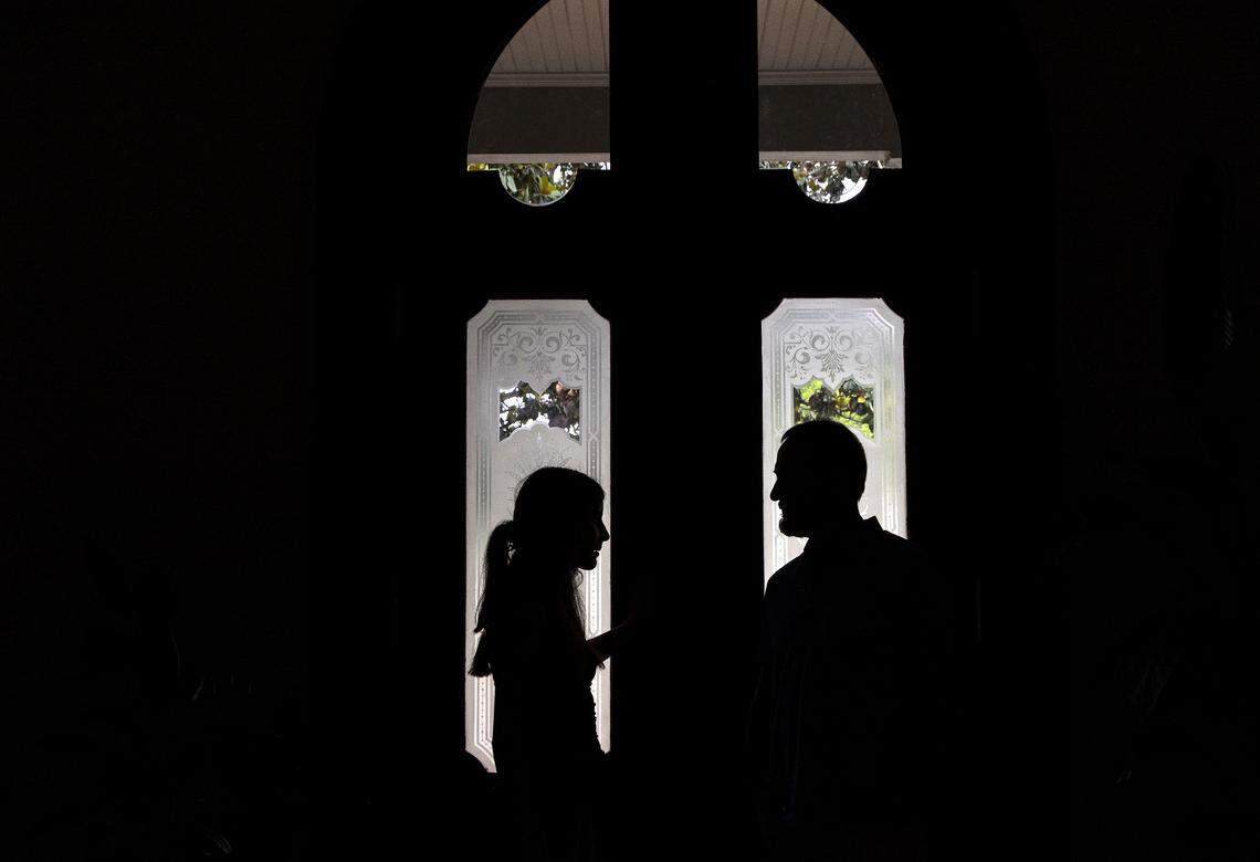 Talia Kuehn is silhouetted by the front door of the Andrews-Duncan House as she talks with Jeff Turpin on Thursday, May 25, 2023, in Raleigh, N.C. Turpin and his partner, Tina Konidaris, moved with their children into the house in February after spending about five years renovating it. The glass front door is original to the house prior to renovations.
