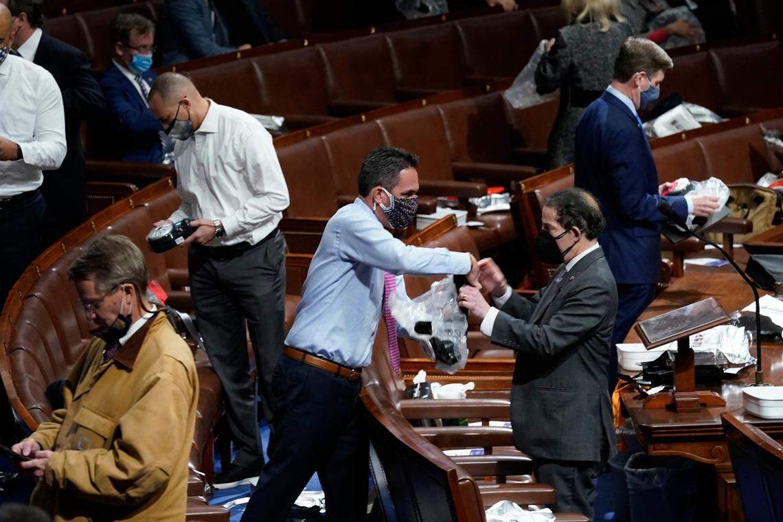 Lawmakers prepare to put on masks on the floor of the House of Representatives as protesters enter the U.S. Capitol, Wednesday, Jan 6, 2021, in Washington.