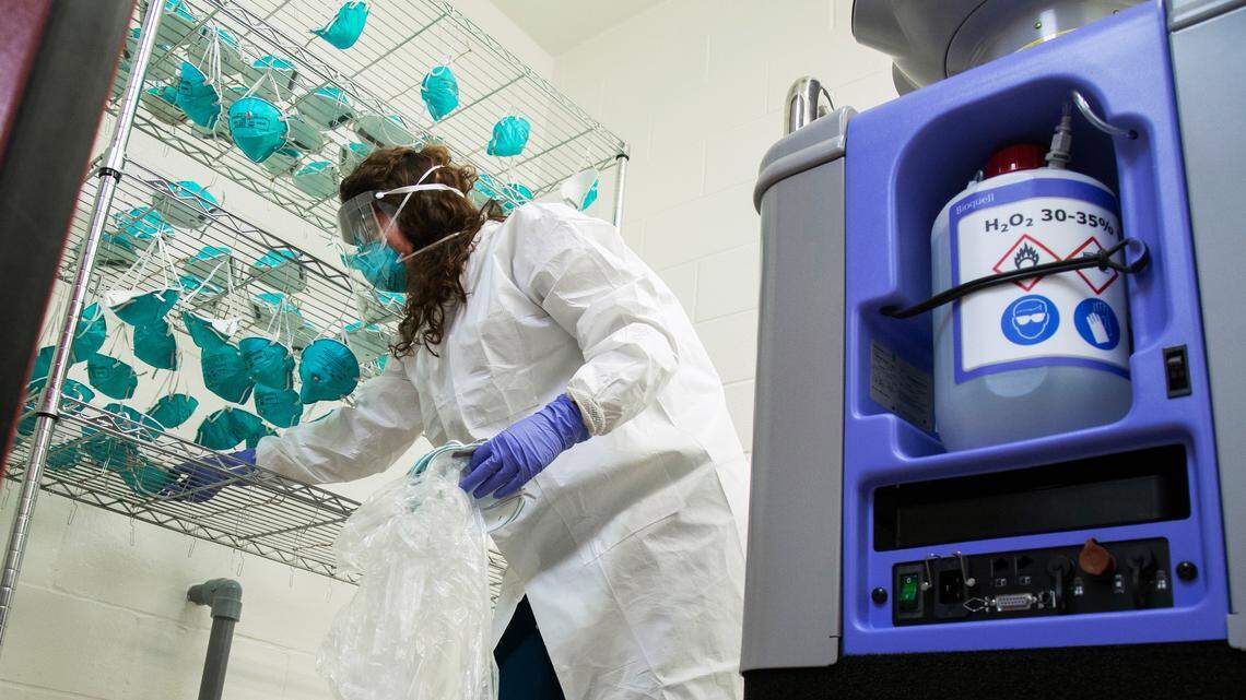 As part of the effort to conserve and reuse N95 masks, Duke occupational and environmental safety employee Andrea Vogel, hangs used masks which will be decontaminated by vaporized hydrogen peroxide. The process uses specialized equipment to aerosolize hydrogen peroxide, which permeates the layers of the mask to kills germs, including viruses, without degrading the mask material.