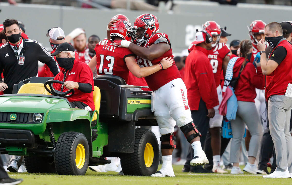 N.C. State’s Grant Gibson (50) hugs quarterback Devin Leary (13) as he is taken off the field after being injured during the second half of N.C. State’s 31-20 victory over Duke at Carter-Finley Stadium in Raleigh, N.C., Saturday, Oct. 17, 2020.