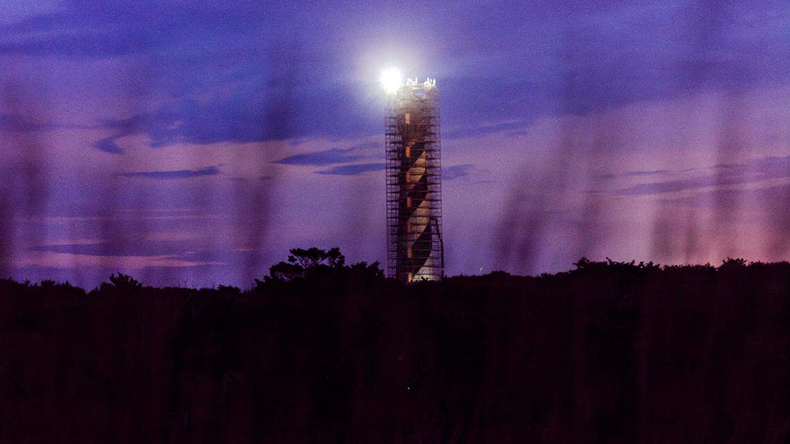 The Cape Hatteras Lighthouse is surrounded by scaffolding against the night sky as it undergoes restoration on Sunday, June 30, 2024. The project is expected to cost $19.2 million and will include replacing 40,000 of its estimated 1,250,000 bricks, replacing rusted or broken metal components and the installation of a near-exact replica of the first-order Fresnel lens.