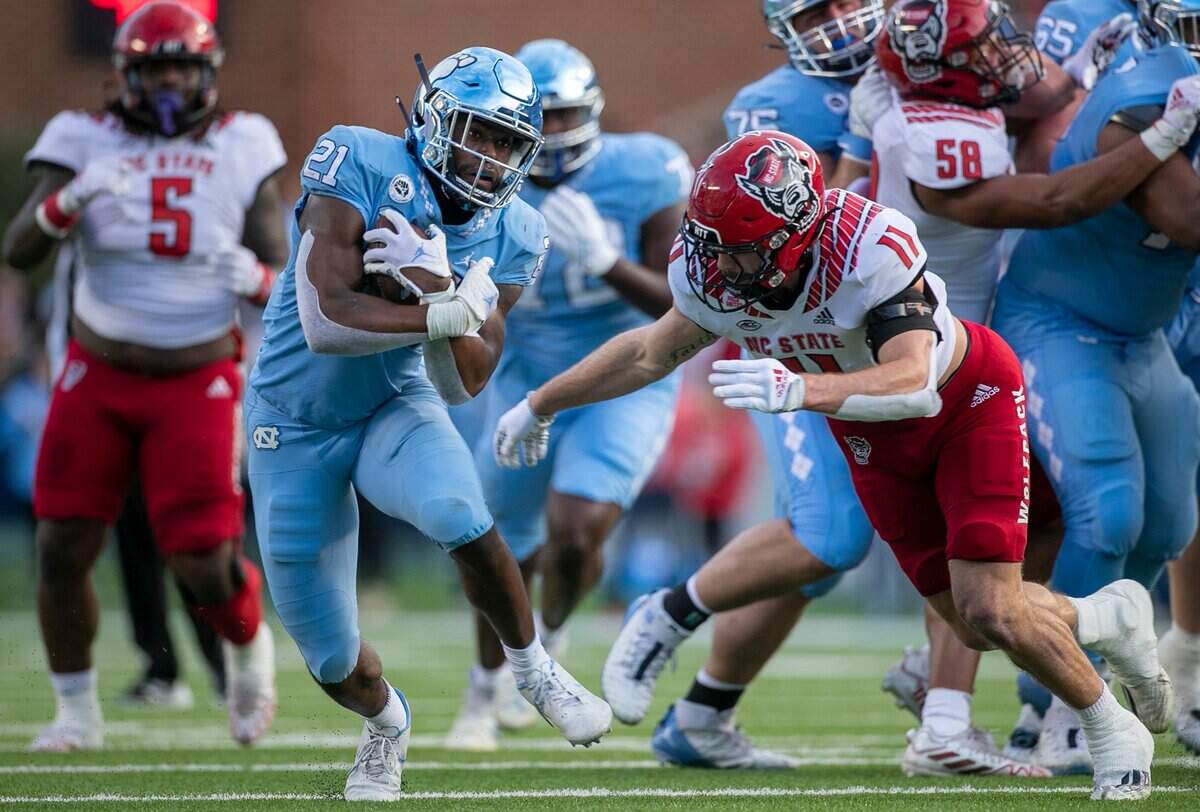 North Carolina’s Elijah Green (21) picks up 11 yards in the first quarter against N.C. State’s Payton Wilson (11) on Friday, November 25, 2022 at Kenan Stadium in Chapel Hill, N.C.