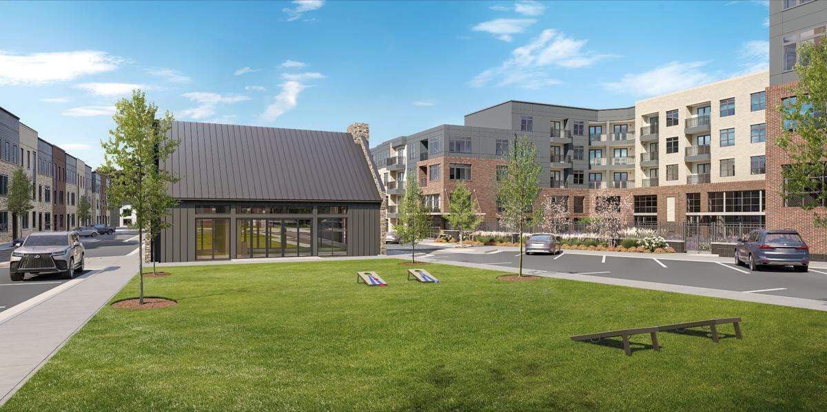 A large green space is flanked by rows of apartments and townhouses at the center of the Aura Booth Park development in Chapel Hill, NC. The mixed-use community is located at the corner of Martin Luther King Jr. Boulevard and Estes Drive.