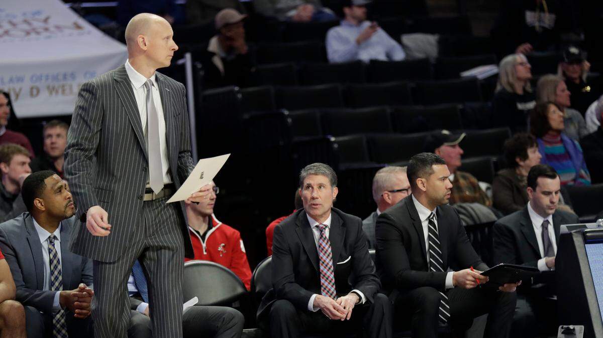 Louisville head coach Chris Mack, left, will be suspended for six games this season as a result of his handling of an extortion case involving former Cardinals assistant coach Dino Gaudio, second from left.