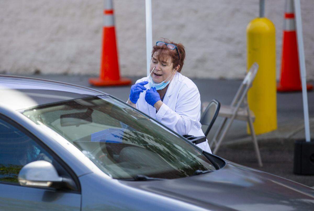 The proper swabbing method is demonstrated for free drive-through coronavirus testing, administered by Walgreens across the street from their Guess Road location in Durham, N.C., on Friday, May 15, 2020.