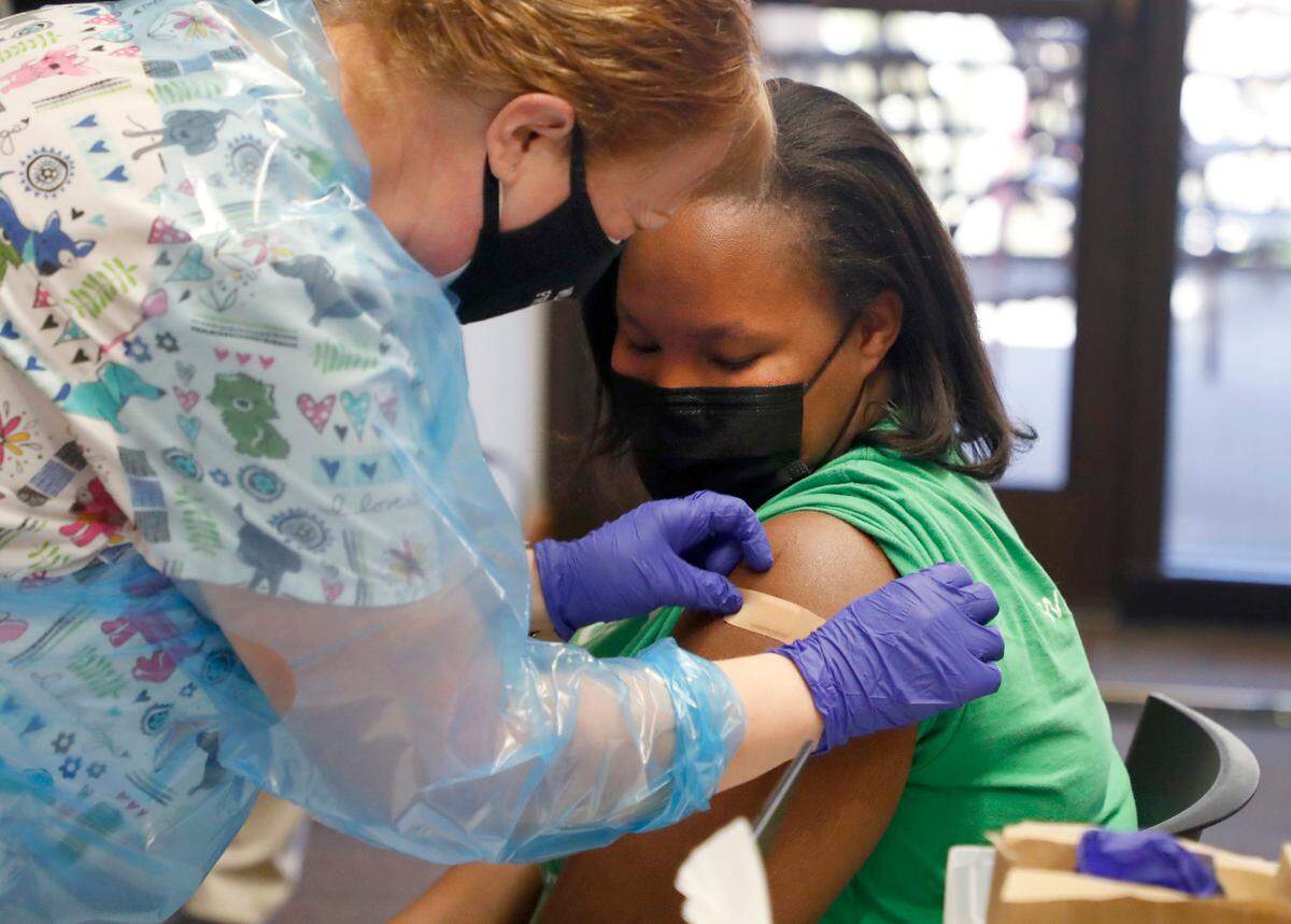 Bianca Lanier, a third grade teacher at Harris Creek Elementary, watches as Sheila Hardesty, RN, puts on a bandage after Lanier received her COVID-19 vaccine during a mass COVID-19 vaccine event at Wake County Commons Building in Raleigh, N.C., Wednesday, February 24, 2021. Wednesday was the first day preK-12 public, private and charter schools, as well as childcare workers, became eligible to begin getting shots.