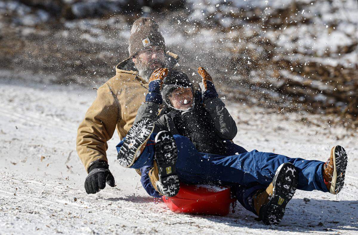 Scott Mizerak and his son Waylon, 10, of Raleigh sled down one of the hills at Dix Park in Raleigh, N.C., Sunday, Feb. 1, 2026.