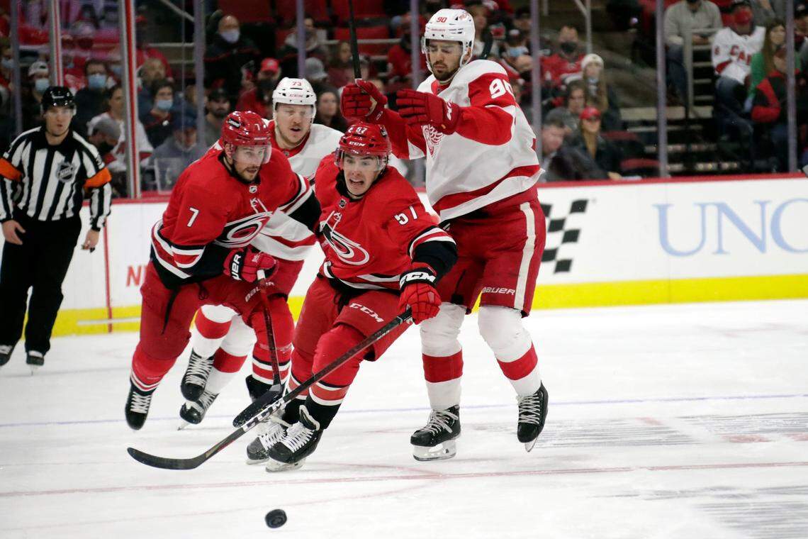 Carolina Hurricanes defenseman Brendan Smith (7) and center Andrew Poturalski (57) battle Detroit Red Wings left wing Adam Erne (73) and center Joe Veleno (90) for the puck during the first period of an NHL hockey game Thursday, Dec. 16, 2021, in Raleigh, N.C. (AP Photo/Chris Seward)