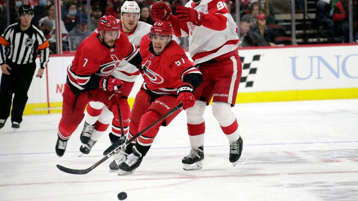 Carolina Hurricanes defenseman Brendan Smith (7) and center Andrew Poturalski (57) battle Detroit Red Wings left wing Adam Erne (73) and center Joe Veleno (90) for the puck during the first period of an NHL hockey game Thursday, Dec. 16, 2021, in Raleigh, N.C. (AP Photo/Chris Seward)
