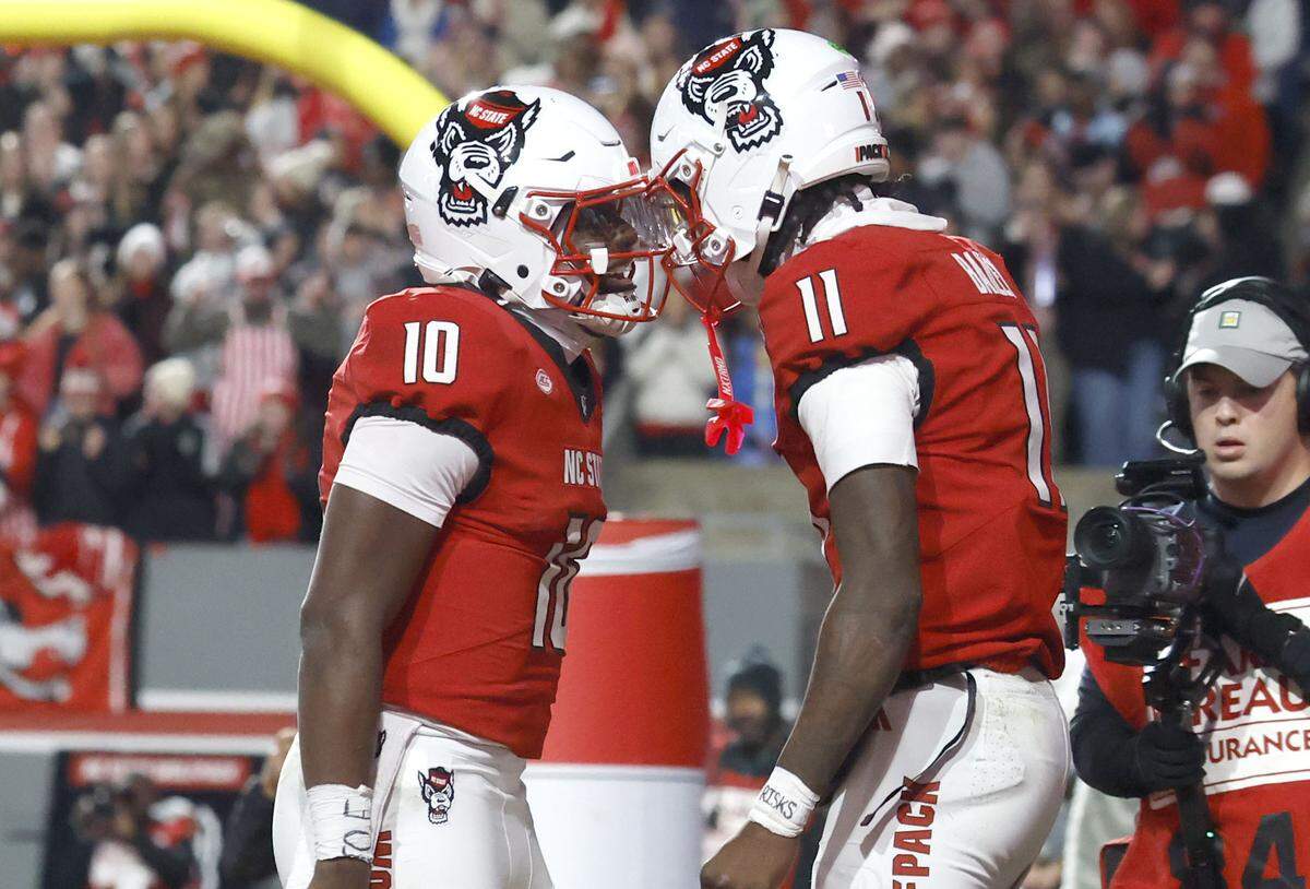 N.C. State quarterback Will Wilson (10) celebrates with quarterback CJ Bailey (11) after Wilson scored on a seven-yard touchdown run in the first half of N.C. State’s game against UNC at Carter-Finley Stadium in Raleigh, N.C., Saturday, Nov. 29, 2025.