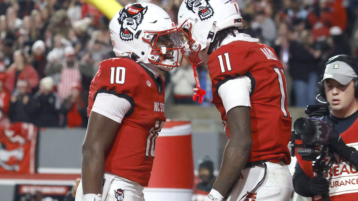 N.C. State quarterback Will Wilson (10) celebrates with quarterback CJ Bailey (11) after Wilson scored a touchdown during N.C. State’s game against UNC at Carter-Finley Stadium in Raleigh, North Carolina, on Nov. 29, 2025.