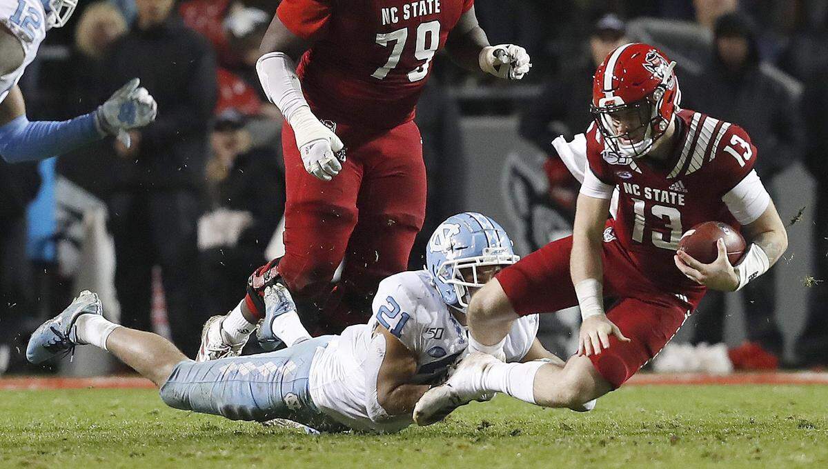 N.C. State quarterback Devin Leary (13) is sacked by North Carolina linebacker Chazz Surratt (21) during the second half of UNC’s 41-10 victory over N.C. State at Carter-Finley Stadium in Raleigh, N.C., Saturday, November 30, 2019.