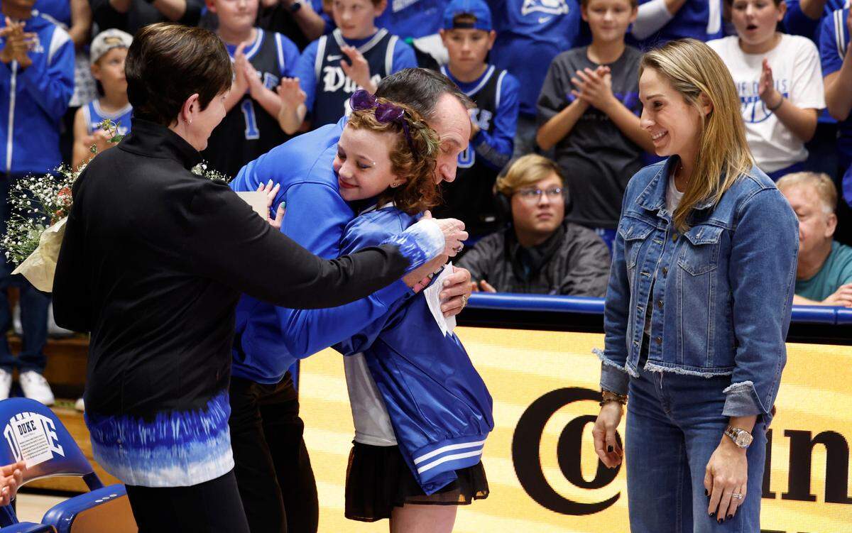 Former Duke head coach Mike Krzyzewski hugs Harper Harrell during a ceremony during the Blue Devils game against Arizona State in the Brotherhood Run Charity Game at Cameron Indoor Stadium in Durham, N.C., Sunday, Oct. 27, 2024. Harrell rang the bell at Cameron Indoor Stadium last season to signal the end of cancer treatment. With Harrell are also Mickie Krzyzewski and Marcelle Scheyer.