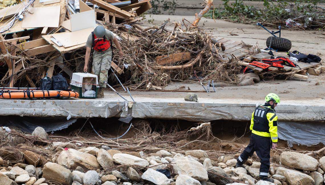 Two people and a dog are escorted to a rescue boat in Chimney Rock, N.C. on Sunday, September 29, 2024.