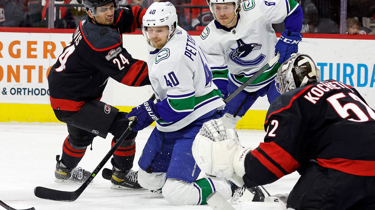 Vancouver Canucks’ Elias Pettersson (40) tries to maintain control of the puck while battling Carolina Hurricanes’ Seth Jarvis (24) in front of Hurricanes goaltender Pyotr Kochetkov (52) during the first period of an NHL hockey game in Raleigh, N.C., Sunday, Jan. 15, 2023. (AP Photo/Karl B DeBlaker)