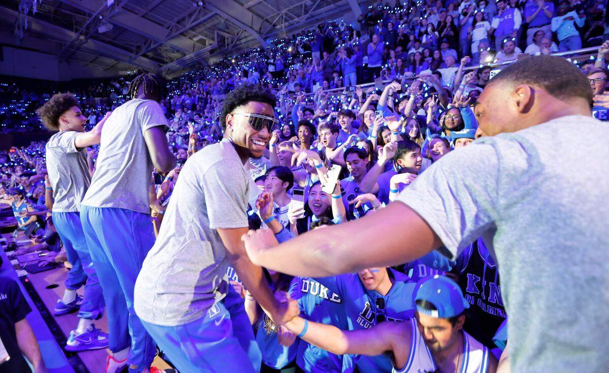 Duke’s Jeremy Roach, center, Jaylen Blakes, right, and teammates jump onto the press row tables after being introduced to celebrate with the Cameron Crazies during Duke’s Countdown to Craziness at Cameron Indoor Stadium in Durham, N.C., Friday, Oct. 21, 2022.