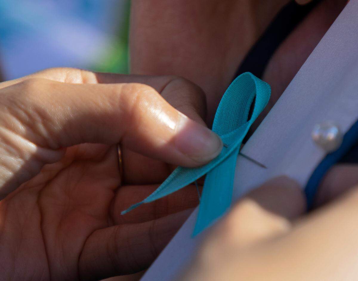 A person attaches a teal ribbon in honor of Hailey Brooks prior to the start of the Raleigh Christmas Parade on Saturday, Nov. 18, 2023. Brooks, an 11-year-old dancer, was struck and killed by a truck during last year’s parade.