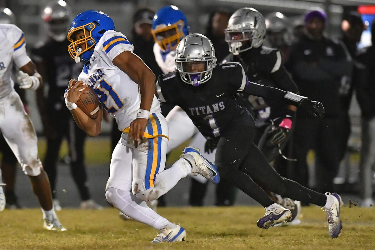 Garner running back Tayden McPhatter (21) runs for yardage past South Garner cornerback Caleb Sykes (1) during the first half.  The South Garner Titans and the Garner Trojans met in a conference football game in Raleigh, N.C. October 17, 2025