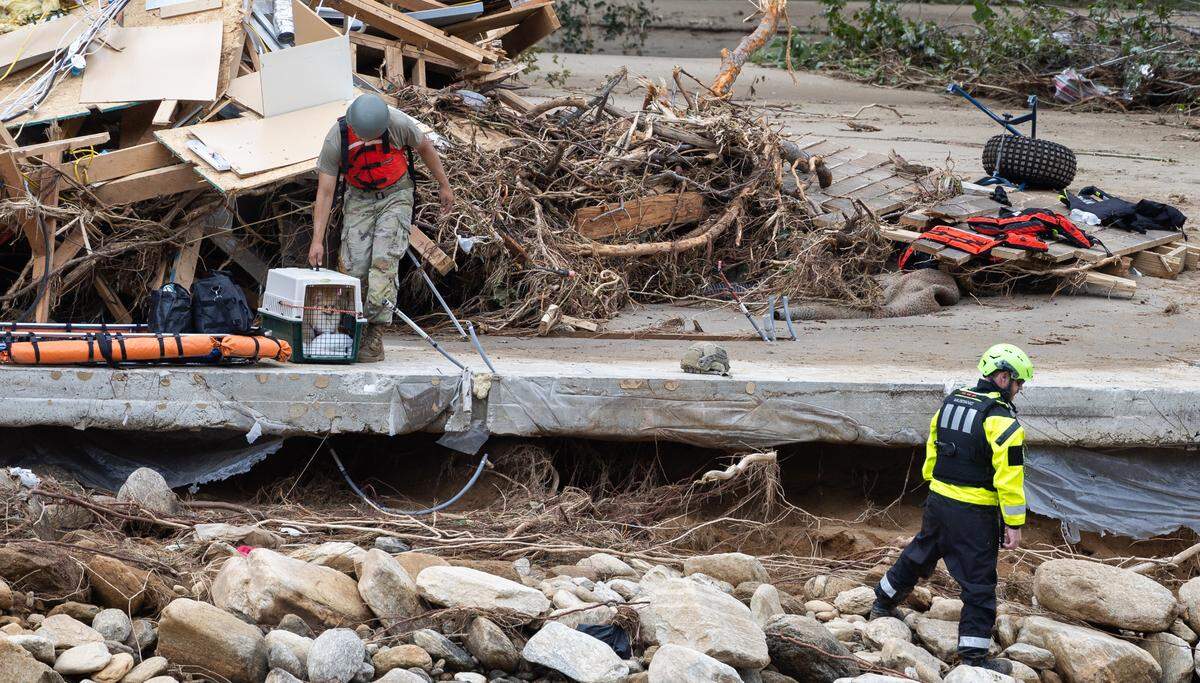 Two people and a dog are escorted to a rescue boat in Chimney Rock, N.C. on Sunday, September 29, 2024.