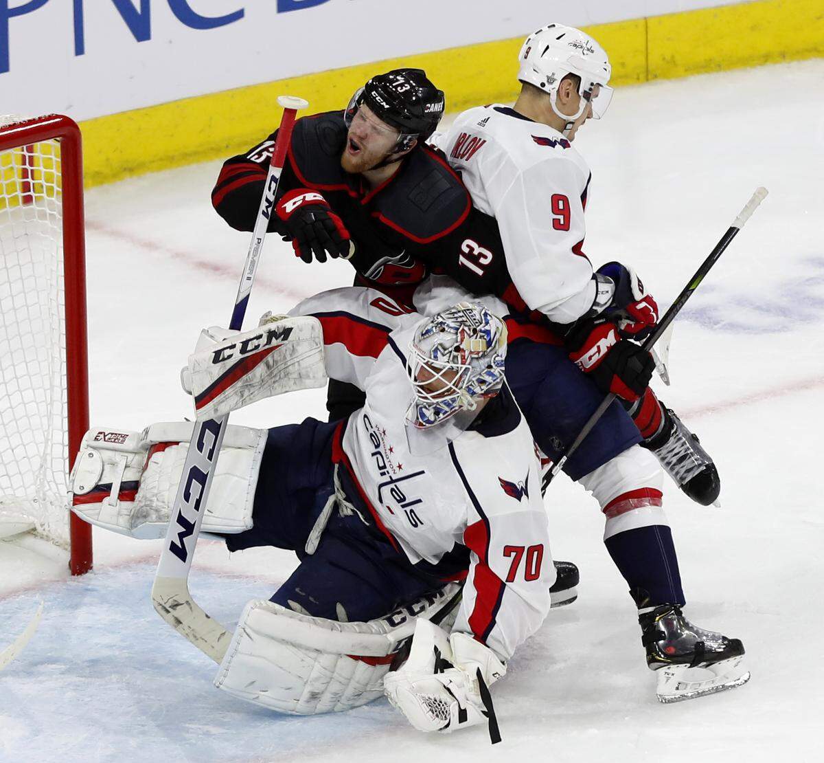 Carolina’s Warren Foegele (13) is crunched between Washington goalie Braden Holtby (70) and Dmitry Orlov (9) during the second period of the Carolina Hurricanes’ game against the Washington Capitals at PNC Arena in Raleigh, N.C., Monday, April 15, 2019.