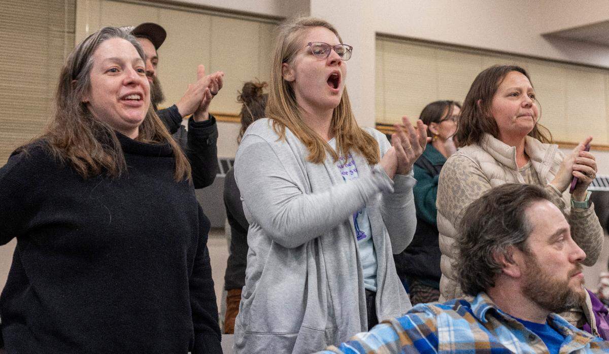 Lili Wang, center, the parent of a Durham student, stands to applaud Durham Board of Education member Millicent Rogers who acknowledged the hardship that this crisis is having on families like hers, during a Board of Education meeting on Thursday, February 8, 2024 at the Staff Development Center in Durham, N.C.