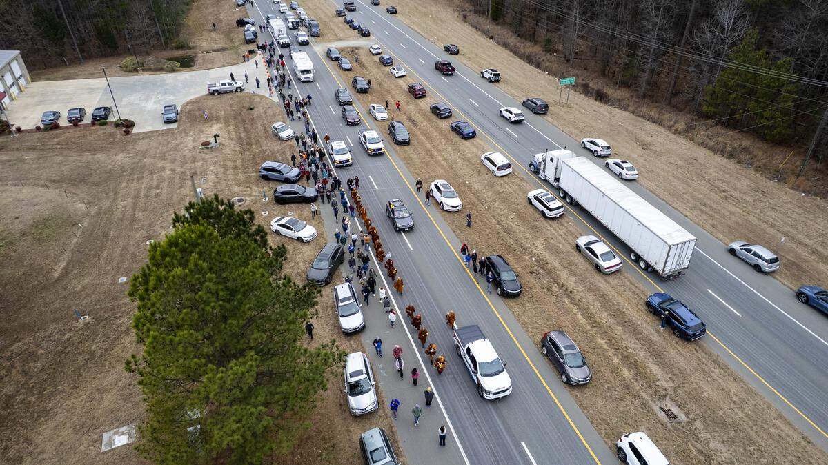 A procession of Buddhist monks walks along U.S. Highway 64 near Wilsonville on Friday, Jan. 23, 2026, as thousands of onlookers line the highway to welcome them. The monks are making a 2,300-mile pilgrimage from Texas to Washington, D.C., as part of the Walk for Peace, an effort to promote peace, compassion and national unity.