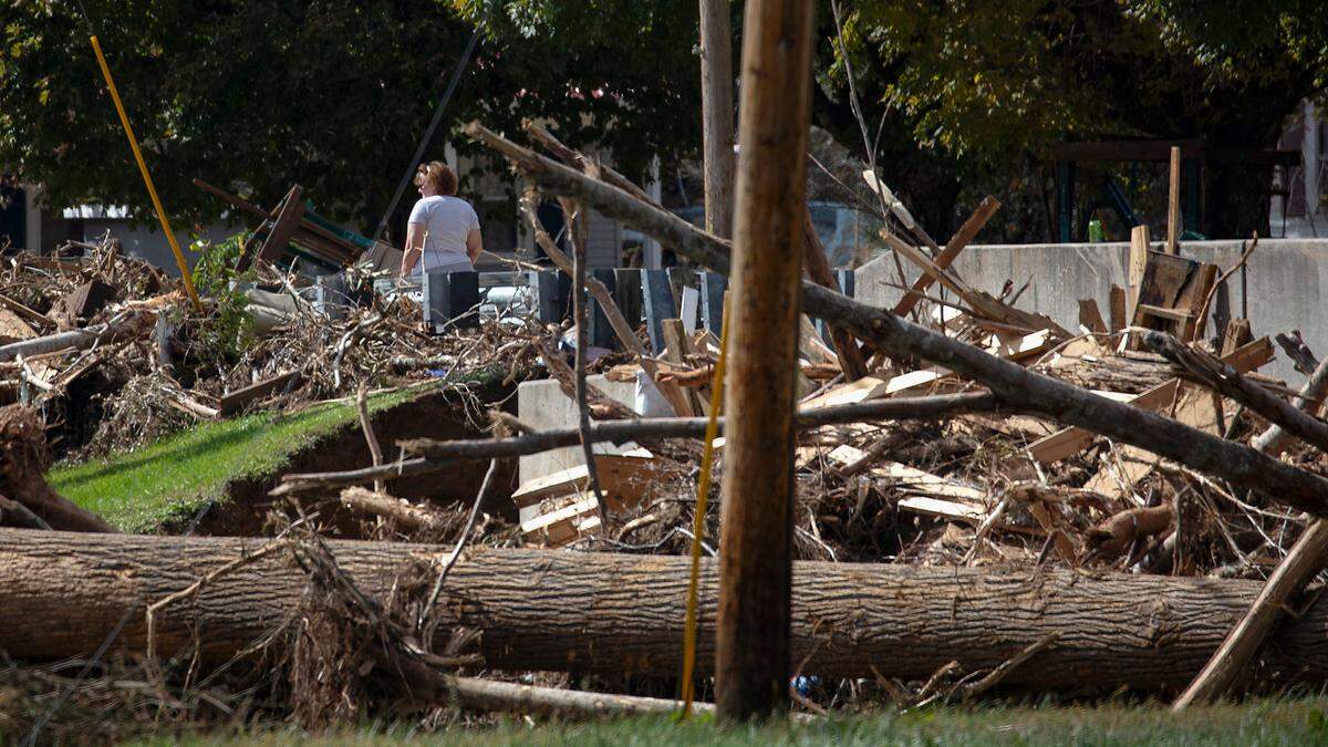 A person walks by debris wedged near a North Toe River bridge in Minneapolis, N.C. on Wednesday, Oct. 2, 2024, days after Hurricane Helene brought heavy flooding to the North Carolina mountains.