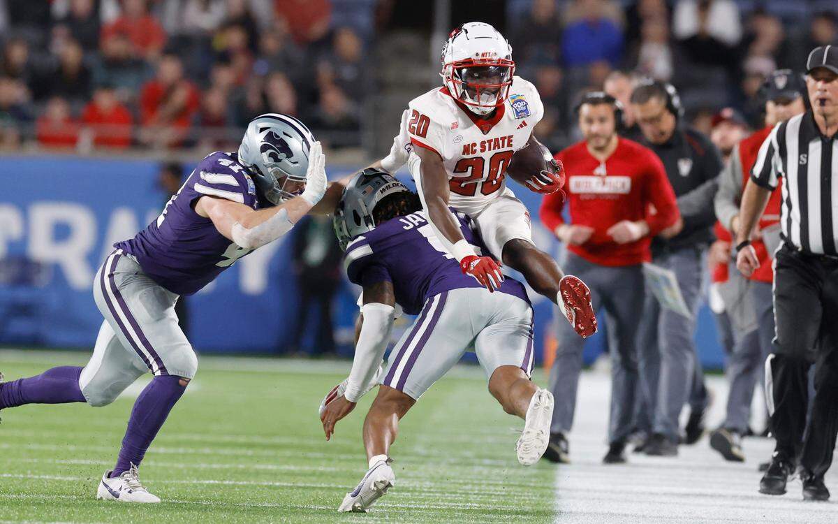 N.C. State running back Kendrick Raphael (20) hurdles over Kansas State cornerback Justice James (5) during the first half of N.C. State’s game against Kansas State in the Pop-Tarts Bowl at Camping World Stadium in Orlando, Fla., Thursday, Dec. 28, 2023.