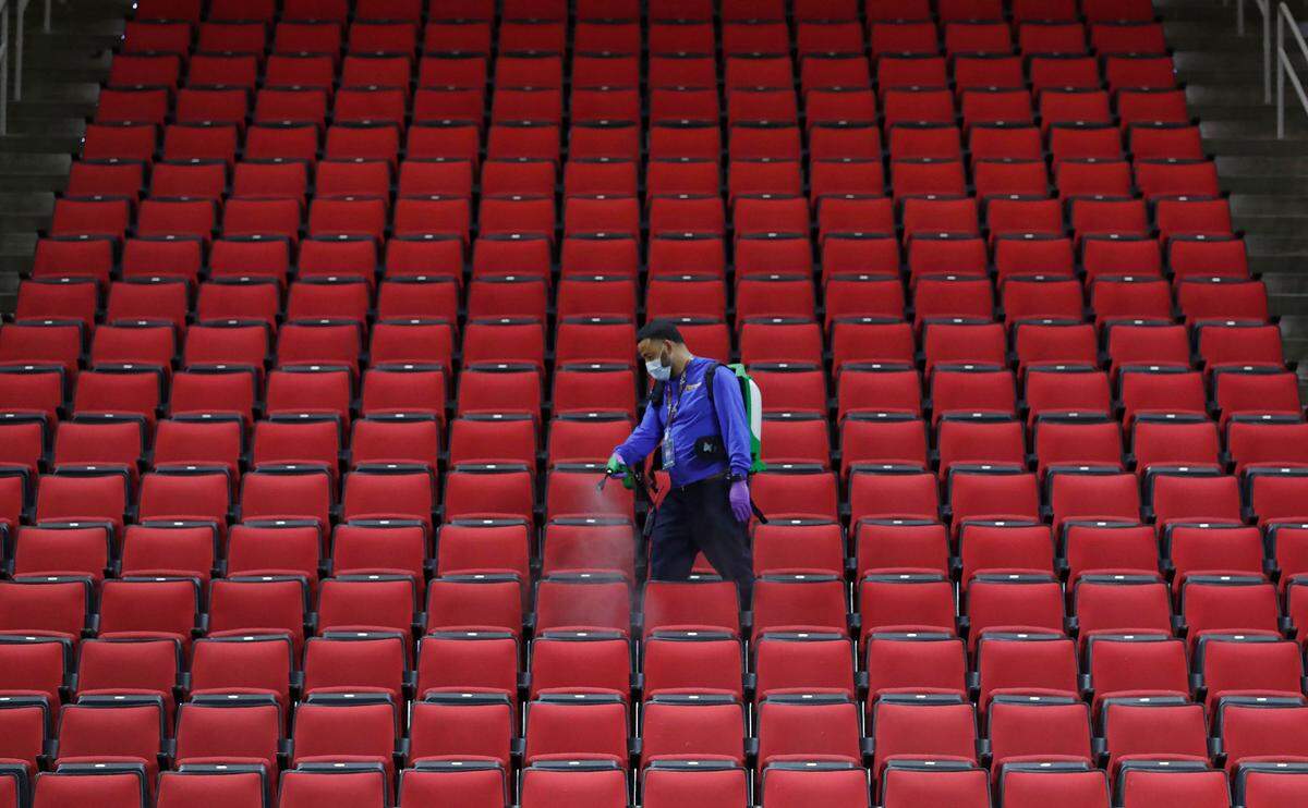 Angel Vettorazzi with Cenplex Building Services sanitizes the seats after N.C. State’s 65-62 victory over Pittsburgh at PNC Arena in Raleigh, N.C., Sunday, February 28, 2021.