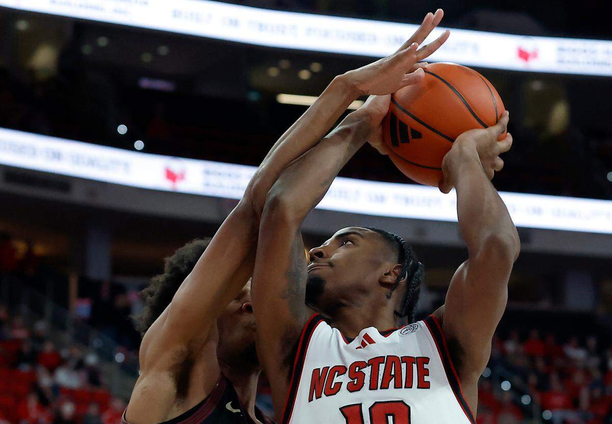 N.C. State’s Marcus Hill drives to the basket against Florida State’s Justin Thomas during overtime of the Wolfpack’s 84-74 win on Saturday, Dec. 7, 2024, at Lenovo Center in Raleigh, N.C.