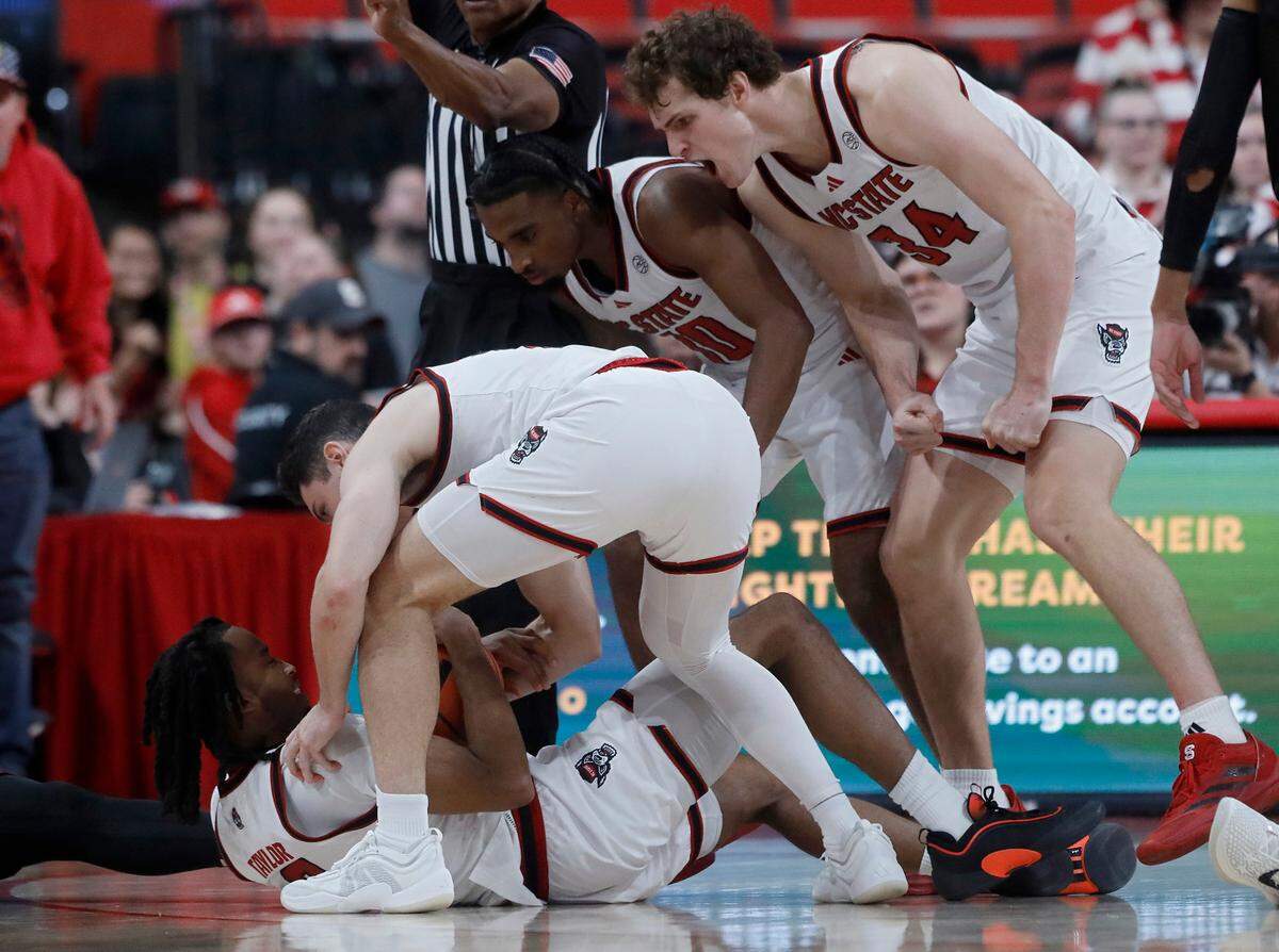 Teammates surround N.C. State’s Jayden Taylor after he drew a foul during the second half of the Wolfpack’s 84-74 overtime win over Florida State on Saturday, Dec. 7, 2024, at Lenovo Center in Raleigh, N.C.
