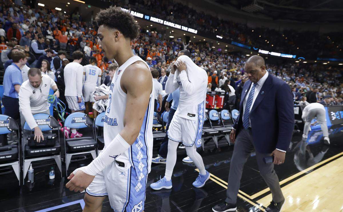 North Carolina's Seth Trimble (7), Elijah Davis and head coach Hubert Davis walk off the court after VCU’s 82-78 overtime victory over UNC in the first round of the NCAA MenÕs Basketball Tournament at  Bon Secours Wellness Arena in Greenville, S.C., Thursday, March 19, 2026.