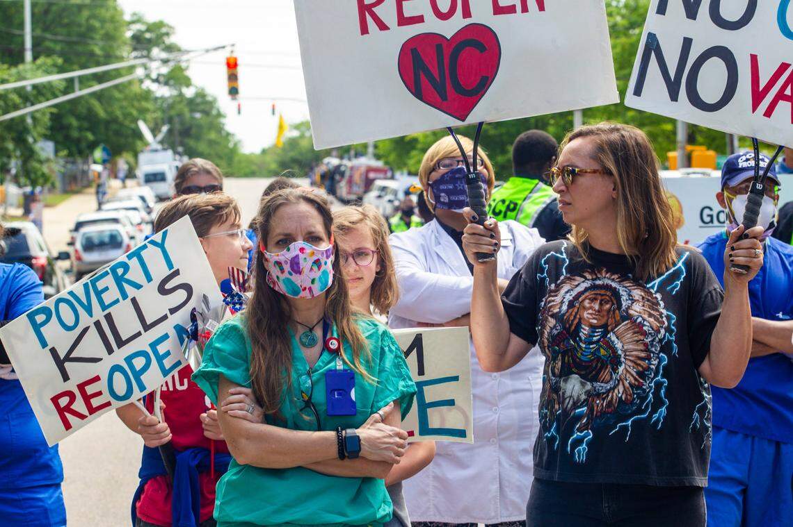 A protesters stand among counter-protesters in front of the North Carolina Legislative Building during a Reopen NC rally in downtown Raleigh Tuesday, April 28, 2020. Protesters were calling for Gov. Roy Cooper to end the restrictions put in place because of the coronavirus pandemic.